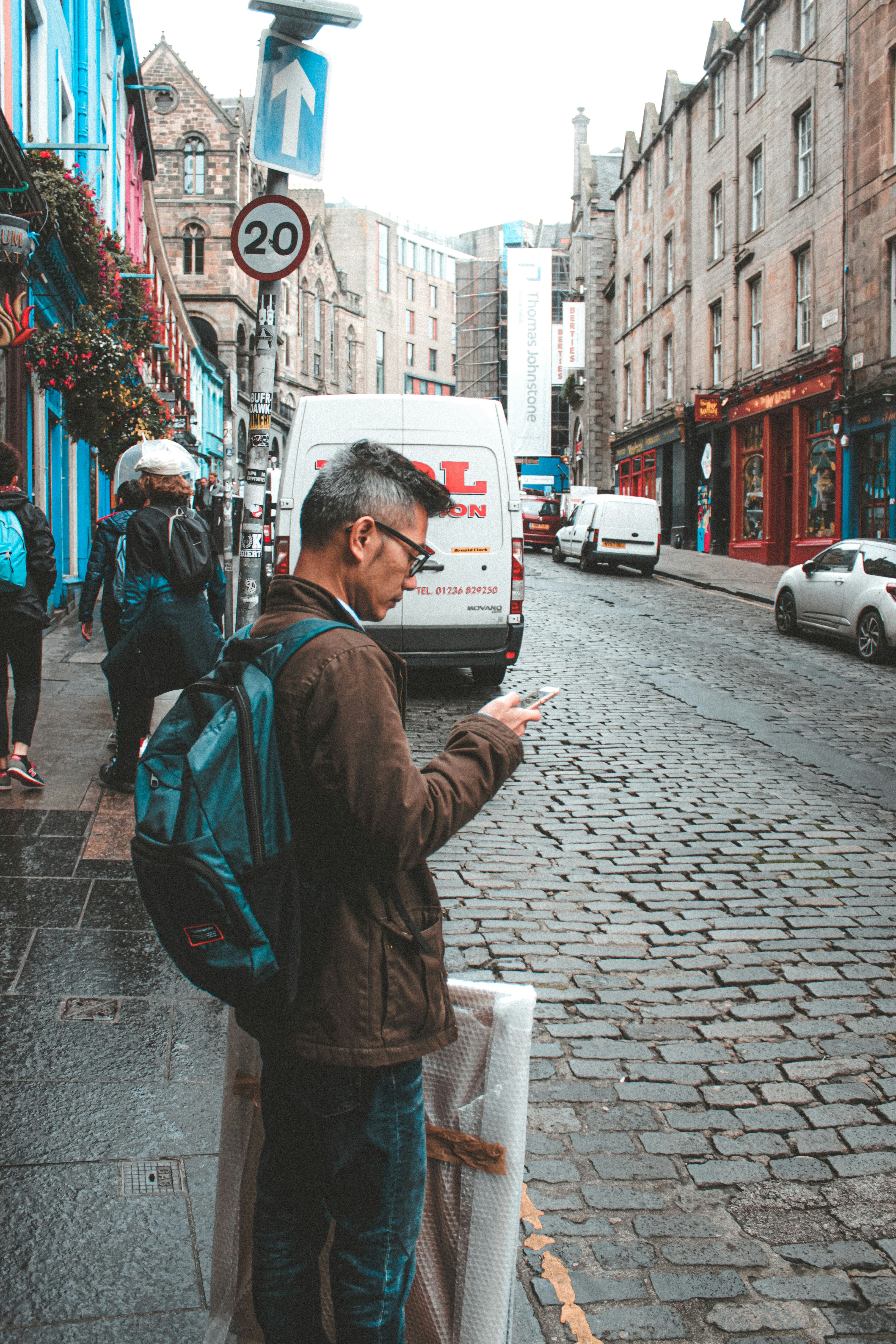 man in blue jacket standing on sidewalk during daytime